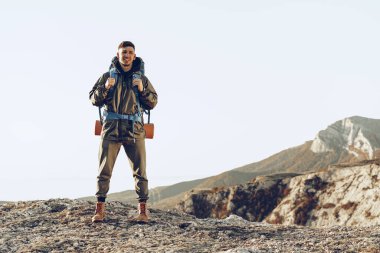 Dağlarda yürüyüş yapan büyük sırt çantalı beyaz bir gezgin.