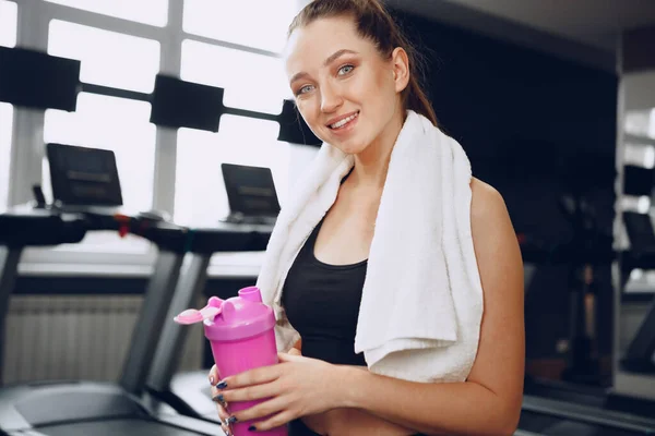 Junge sportliche Frau trinkt nach dem Training einen Drink im Fitnessstudio — Stockfoto