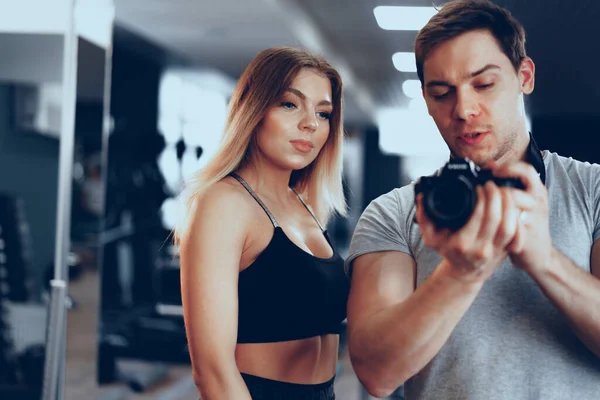 Fotógrafo tirando uma foto de uma jovem em forma em um ginásio — Fotografia de Stock