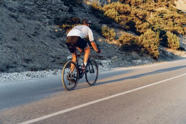 Gündoğumunda dağ yolunda profesyonel bisikletçi.