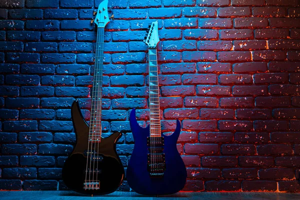 Elektrische gitaar in neon licht tegen donkere muur — Stockfoto
