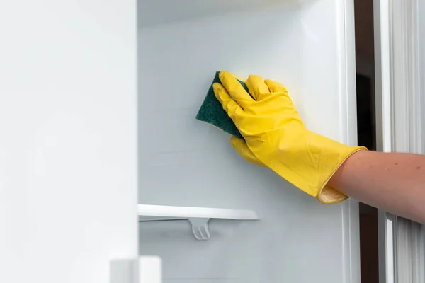 Ręka kobiety w żółtej rękawiczce czyszczącej półkę na lodówkę — Zdjęcie stockowe