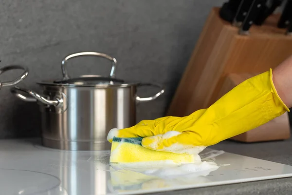 Женские руки в жёлтых перчатках, моющие электрическую плиту губкой — стоковое фото