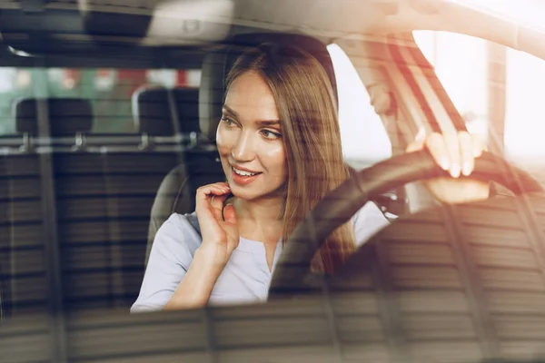 Attraktive junge Frau sitzt in Neuwagen im Showroom — Stockfoto