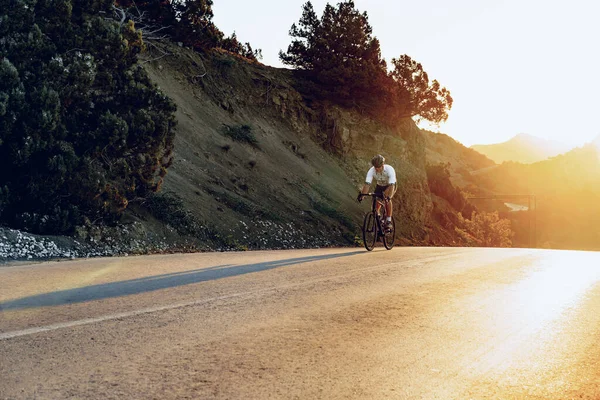 Gündoğumunda dağ yolunda profesyonel bisikletçi.