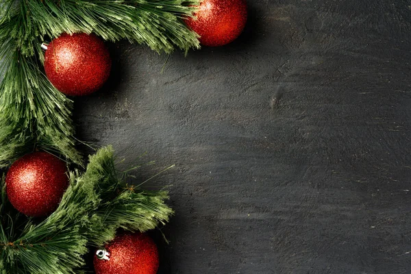 Χριστουγεννιάτικο φόντο με κλαδιά ελάτης και κόκκινα στολίδια σε μαύρο — Φωτογραφία Αρχείου