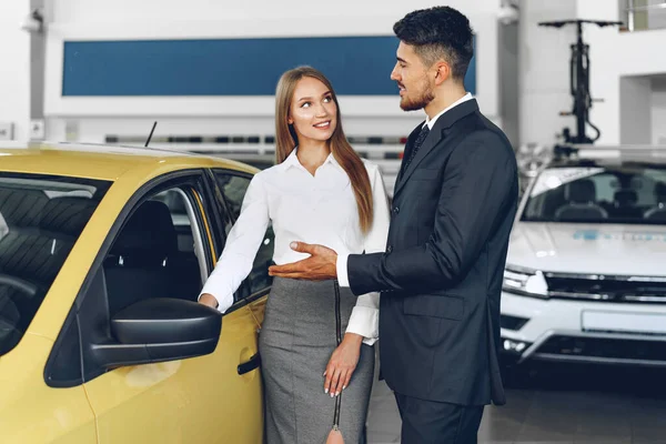 Homem carro revendedor mostrando uma mulher comprador um novo carro — Fotografia de Stock