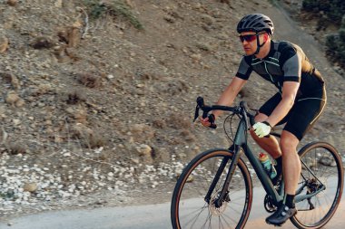 Gündoğumunda dağ yolunda profesyonel bisikletçi.