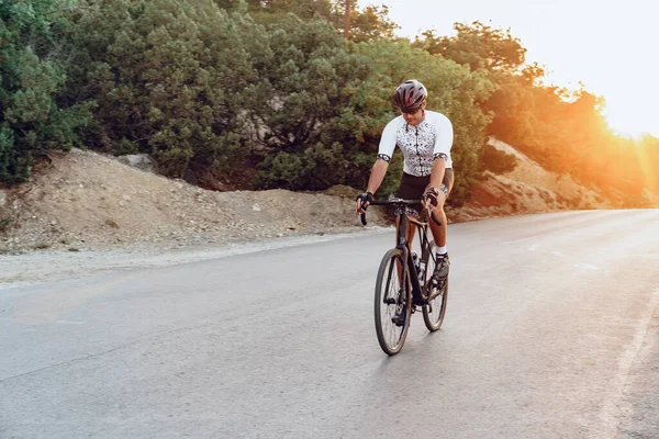 Uomo ciclista pedalando su una bici da strada all'aperto al tramonto — Foto Stock