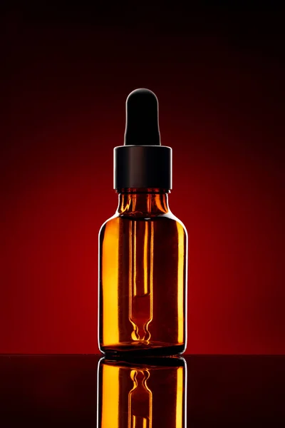 Butelka szklana z olejkiem kosmetycznym na ciemnym tle — Zdjęcie stockowe