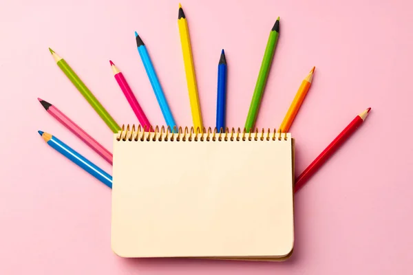 Open notepad and color pencils on paper background — Stock Photo, Image