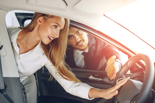 Дилер автомобілів чоловіка показує жінці покупця нового автомобіля — стокове фото