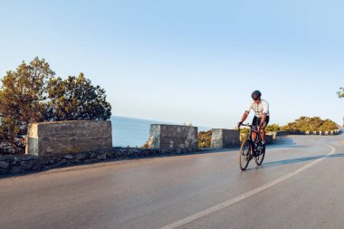 Bisikletli bir adam gün batımında açık havada bisiklet sürüyor.