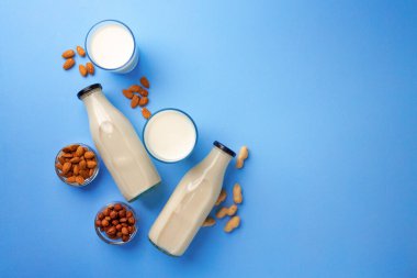 Mavi arka planda çeşitli fındıklı süt şişeleri.
