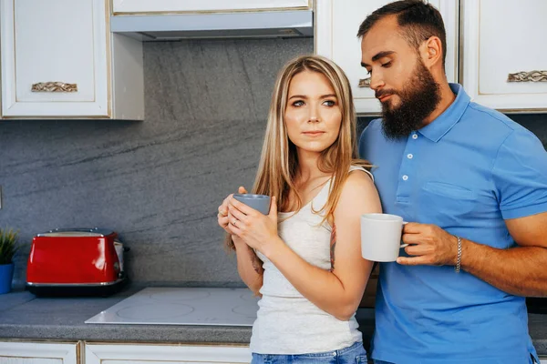 Mujer joven y hombre relajándose con tazas de té en casa en la cocina — Foto de Stock