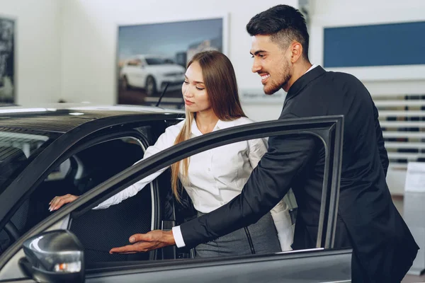 Homem carro revendedor mostrando uma mulher comprador um novo carro — Fotografia de Stock