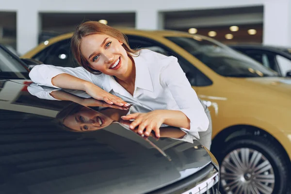 Schöne junge Frau berührt ihr neues Auto mit Vergnügen — Stockfoto