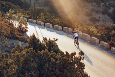 Gündoğumunda dağ yolunda profesyonel bisikletçi.