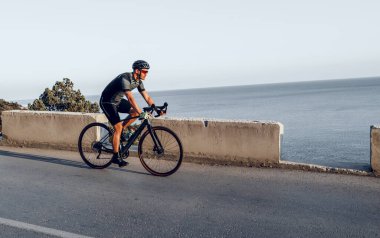 Bisikletli bir adam gün batımında açık havada bisiklet sürüyor.