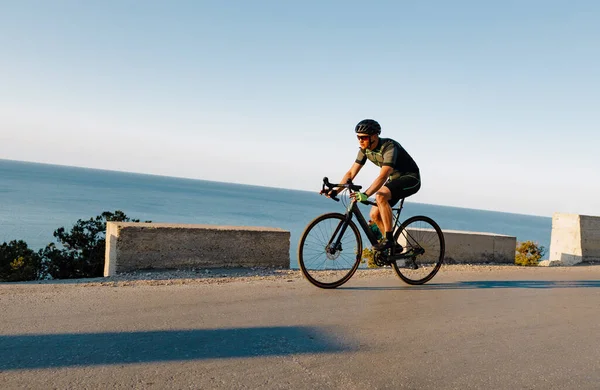 Atleta ciclistico sportivo uomo cavalcando su strada costiera — Foto Stock