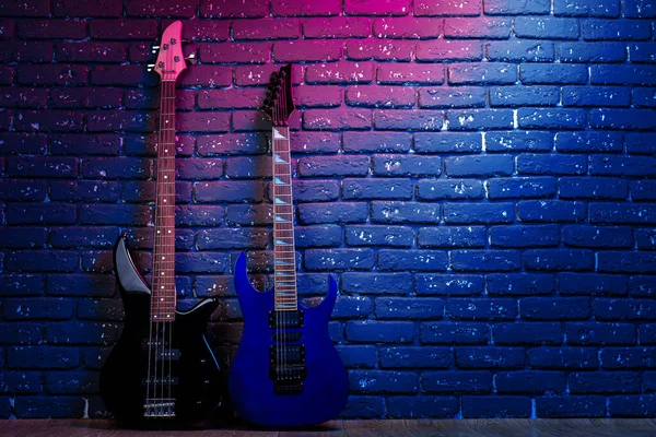 Elektrische gitaar in neon licht tegen donkere muur — Stockfoto