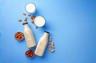 Mavi arka planda çeşitli fındıklı süt şişeleri.
