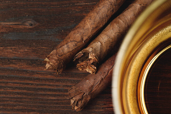 Стакан виски и сигары на деревянном столе