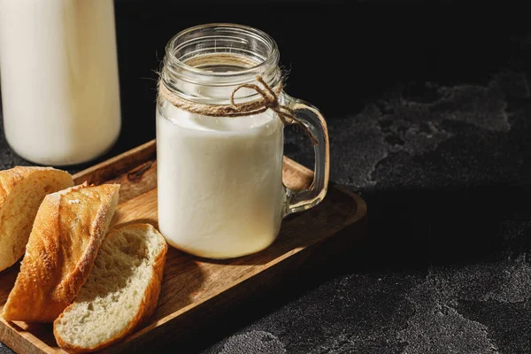 Egy pohár tejet szeletelt bagettel, fa táblán. — Stock Fotó