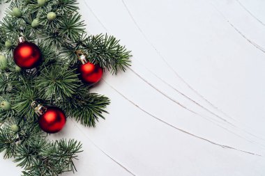 Beyaz arka planda takılarla süslenmiş Noel ağacı dalları