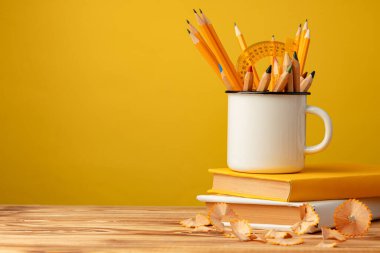 Keskin kalemli metal bardak ve tahta masa üzerinde kalem talaşı.