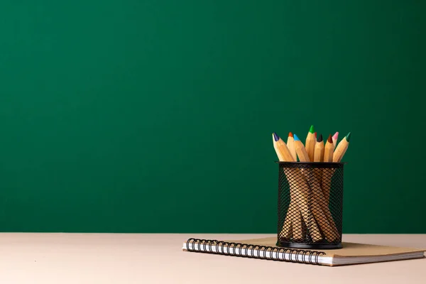 School supplies on wooden desk against green chalkboard — Stock Photo, Image