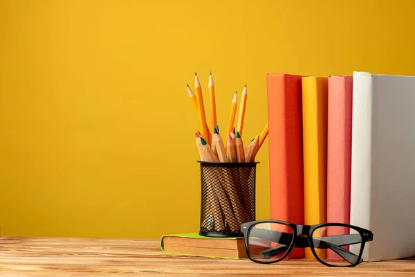 Copo de escritório com lápis e artigos de papelaria contra fundo amarelo — Fotografia de Stock