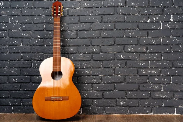 Una guitarra en el suelo contra la pared de ladrillo blanco —  Fotos de Stock