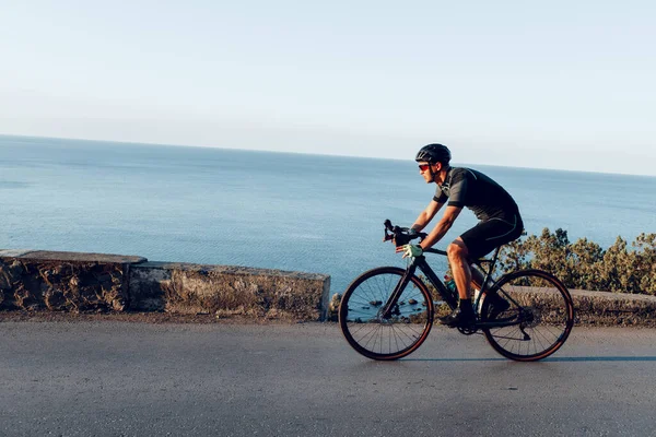 Atleta ciclistico sportivo uomo cavalcando su strada costiera — Foto Stock