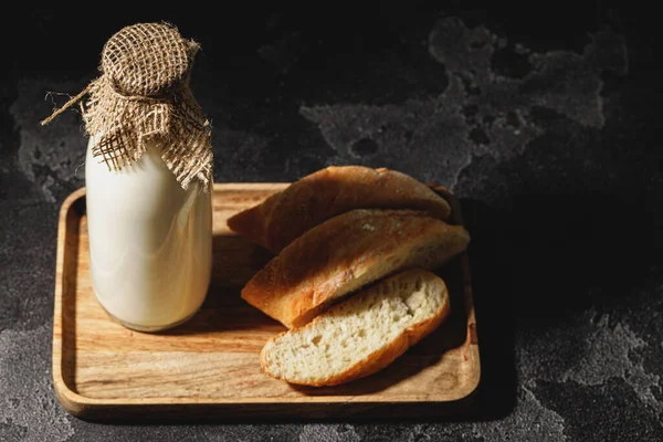 Dilimlenmiş baget ekmekli bir şişe süt.