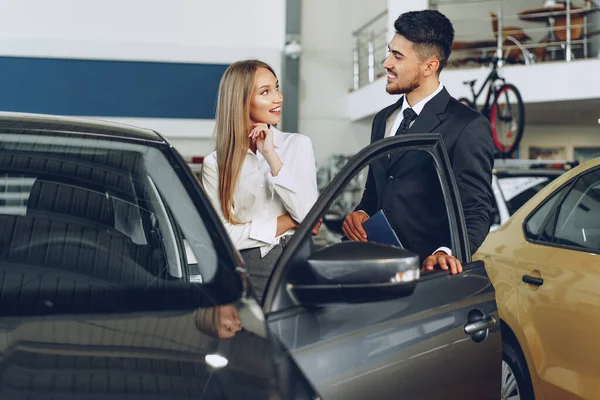 Дилер автомобілів чоловіка показує жінці покупця нового автомобіля — стокове фото