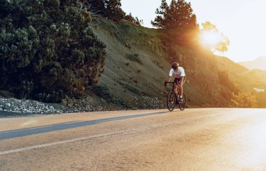 Gündoğumunda dağ yolunda profesyonel bisikletçi.