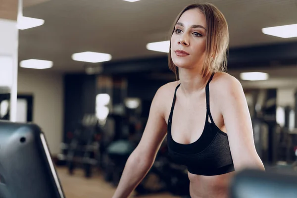 Ziemlich fitte Frau im schwarzen Sportanzug beim Training auf dem Laufband — Stockfoto