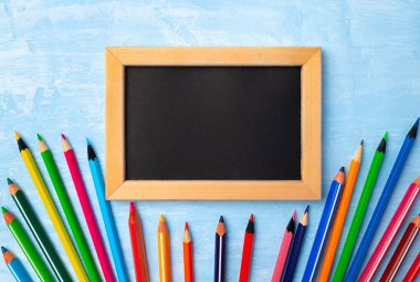 Etrafı renkli kalemlerle çevrili ahşap çerçeveli küçük tahtalar.