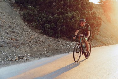 Gündoğumunda dağ yolunda profesyonel bisikletçi.