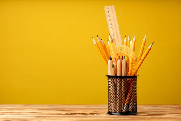 Sarı zemin üzerinde kalem ve kırtasiye malzemesi olan ofis kupası — Stok fotoğraf