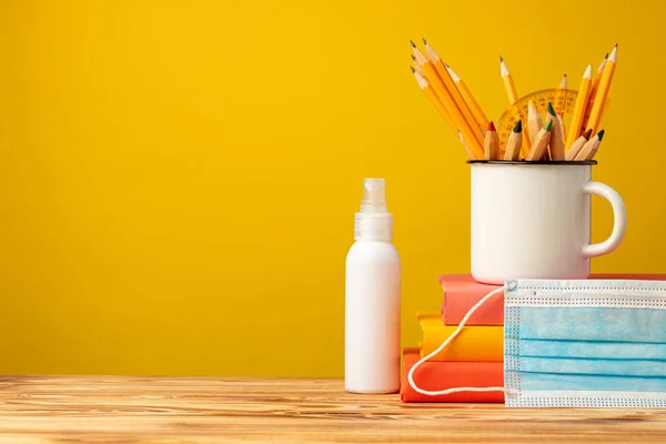 Material escolar e máscara médica na mesa — Fotografia de Stock