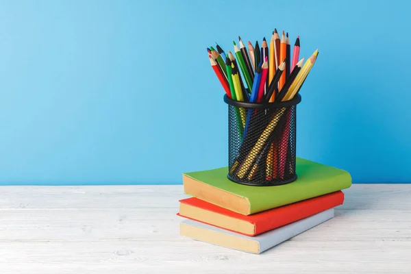 Чашка цветных карандашей и стопка книг — стоковое фото