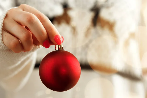 Mano de una mujer en jersey festivo con adornos navideños con luces borrosas — Foto de Stock