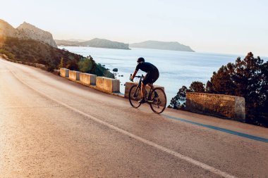 Bisikletli bir adam gün batımında açık havada bisiklet sürüyor.