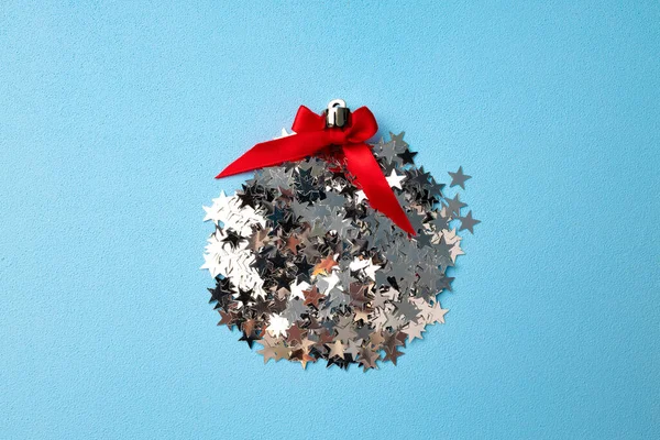 Weihnachtskugel aus Konfetti auf blauem Hintergrund flach gelegt — Stockfoto