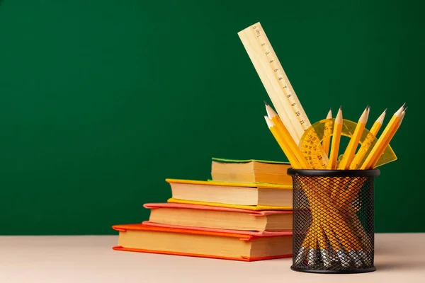 Materiały szkolne na drewnianym biurku z zieloną tablicą — Zdjęcie stockowe