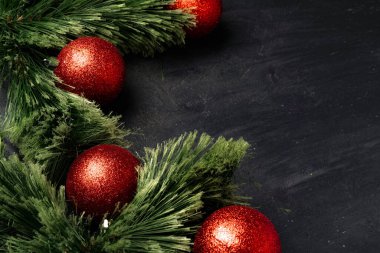 Noel arkaplanı köknar ağacı dalları ve siyah üzerine kırmızı takılar