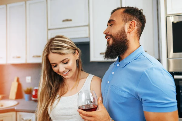 기쁨에 넘쳐 미소짓는 부부가 주방에서 요리하고 포도주를 마시는 모습 — 스톡 사진