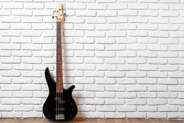 Una guitarra en el suelo contra la pared de ladrillo blanco — Foto de Stock